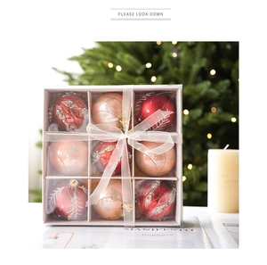 Close-up of 9-piece burgundy and champagne Christmas baubles in a gift box with white bow