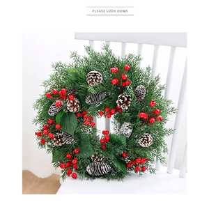 Detail of Christmas pine needle wreath with red berries and snow-dusted pine cones