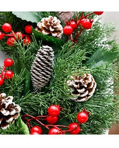 Detail of Christmas pine ring featuring green needles, red berries and snow-tipped pinecones
