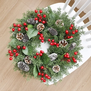 Christmas candle ring with pine needles, cones and red berries on a white wooden chair
