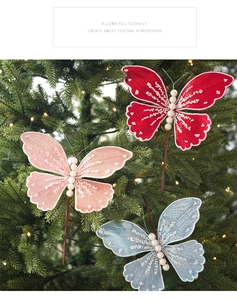 Detail of glitter fabric butterfly ornaments with white pearls on a lighted Christmas tree