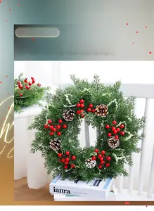 Détail de couronne de Noël avec baies rouges et pommes de pin sur chaise blanche