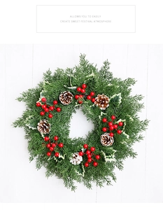 Détail de couronne de Noël avec aiguilles de pin, baies rouges et pommes de pin