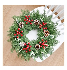 Détail d'une couronne de Noël avec baies rouges et pommes de pin sur chaise blanche
