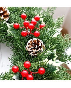 Détail de guirlande de Noël avec baies rouges, pommes de pin enneigées et feuilles de houx
