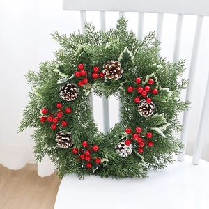 Couronne de Noël avec aiguilles de pin, baies rouges et pommes de pin enneigées sur chaise