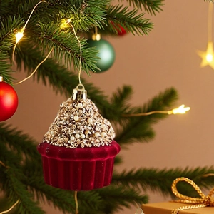 Detail eines roten beflockten Cupcake-Weihnachtsschmucks mit goldenen Pailletten