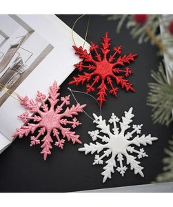 Close-up of glittery red, pink, and white snowflake ornaments with hanging strings