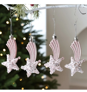 Detail of pink meteor-shaped Christmas ornaments with glitter finish hanging on white branches
