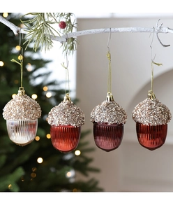 Close-up of four metallic acorn Christmas ornaments with glitter caps on white branches