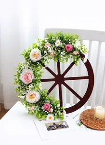 Detail of wooden wheel Christmas wreath with pink roses and evergreen leaves
