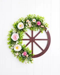 Detail of wooden wagon wheel wreath with green foliage and delicate floral accents