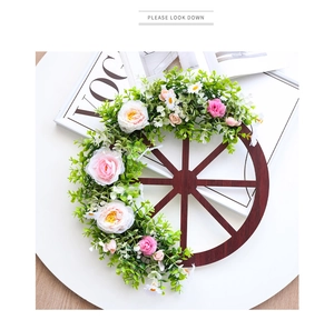 Detailed close-up of a wooden wheel floral wreath with green leaves and roses