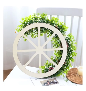 Detail of a rustic wooden wagon wheel frame with lush green faux leaf foliage