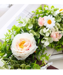 Detail of faux roses and eucalyptus leaves on a rustic wooden wheel Christmas wreath