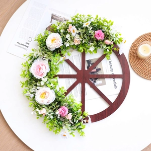 Rustic wooden wagon wheel wreath with pink roses and green foliage for Christmas decor