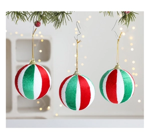 Detalle de bolas de Navidad con rayas rojas verdes y blancas en ramas de pino