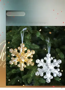Detailed view of light gold and clear snowflake ornaments hanging on a lit Christmas tree