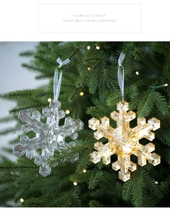 Close-up of sparkling faceted snowflake ornaments hanging on a green Christmas tree branch