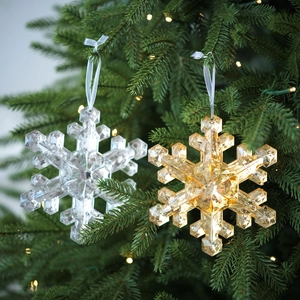 Sparkling transparent and amber acrylic snowflake ornaments on a lit Christmas tree