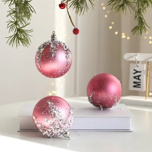 Palline di Natale rosa opaco con paillettes argento e perle appese a un ramo di pino