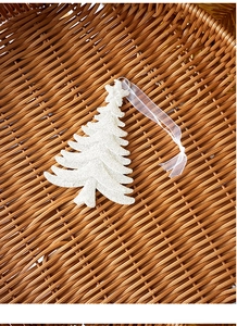 Close-up of a white glittery Christmas tree hanging ornament with a delicate ribbon strap