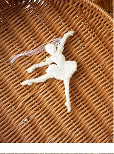 Close-up of a white glittery ballerina ornament with a ribbon on a brown basket base