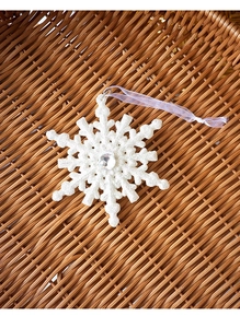 Detailed white glitter snowflake ornament with center rhinestone on rustic woven background