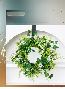 Close-up of a festive artificial green wreath with foliage and white flowers decoration