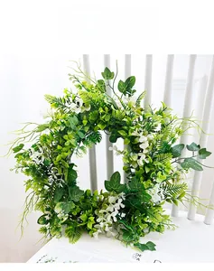 Detail of lush green artificial wreath with ivy and fern leaves on white wooden chair