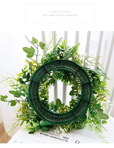 Detail of the green artificial foliage wreath base with small white flowers for DIY decor