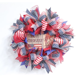 Close-up of Independence Day wreath with red blue ribbons and wooden Happy 4th of July sign