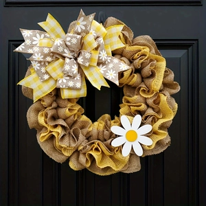 Detailed macro view of yellow daisy burlap wreath hanging on a dark textured wooden door