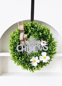 Close-up of artificial eucalyptus wreath with daisies, burlap bow and Merry Christmas sign