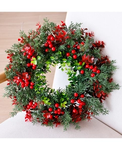 Detail van een kerstkrans met eucalyptusbladeren en rode bessen op een witte stoel