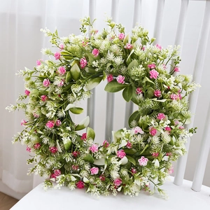 Artificial spring daisy and bee festival wreath with pink flowers on a white chair