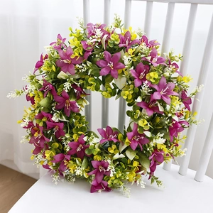 Spring wreath with purple flowers and yellow daisies on a white wooden chair