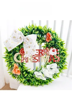 Detail of Christmas wreath with green foliage, Merry Christmas sign, and white bow