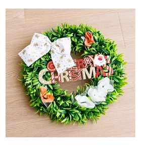 Detail of Christmas wreath with green leaves, reindeer bow and Merry Christmas sign