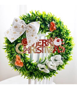 Detail of Christmas wreath with white bow and Merry Christmas sign on white chair