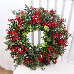 Kerstkrans met rode bessen en groene dennennaalden op een witte houten stoel