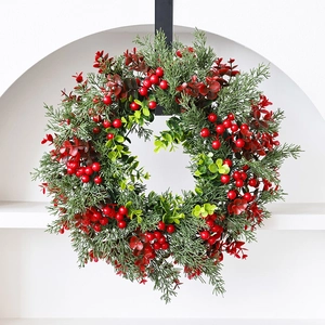 Kerstkrans met rode bessen en eucalyptusbladeren hangend aan een witte muurnis