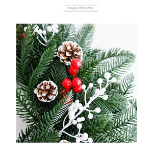 Détail de couronne de Noël avec aiguilles de pin, baies rouges et pommes de pin naturelles