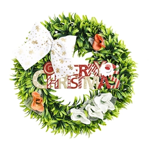Artificial Christmas wreath with green leaves, golden star bow and Merry Christmas sign