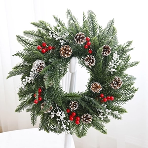 Couronne de Noël en PE avec pommes de pin et baies rouges sur une chaise blanche