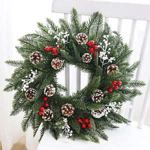 Couronne de Noël verte avec pommes de pin et baies rouges sur une chaise blanche