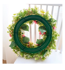 Détail du support en plastique vert foncé à l'arrière d'une couronne de fleurs roses