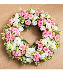 Vue de dessus d'une couronne ronde de roses artificielles roses sur bois clair
