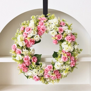 Couronne de roses artificielles roses et blanches pour porte sur fond d'arche blanche