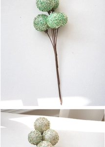 Detailed view of green sequined decorative balls on brown stems for floral arrangements